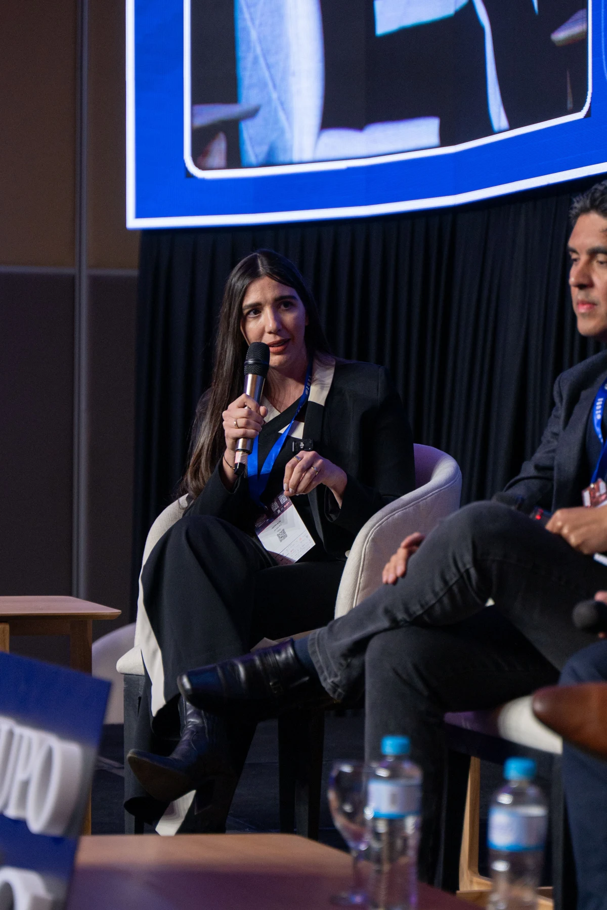 Jazmin Arias participando en un panel con un micrófono